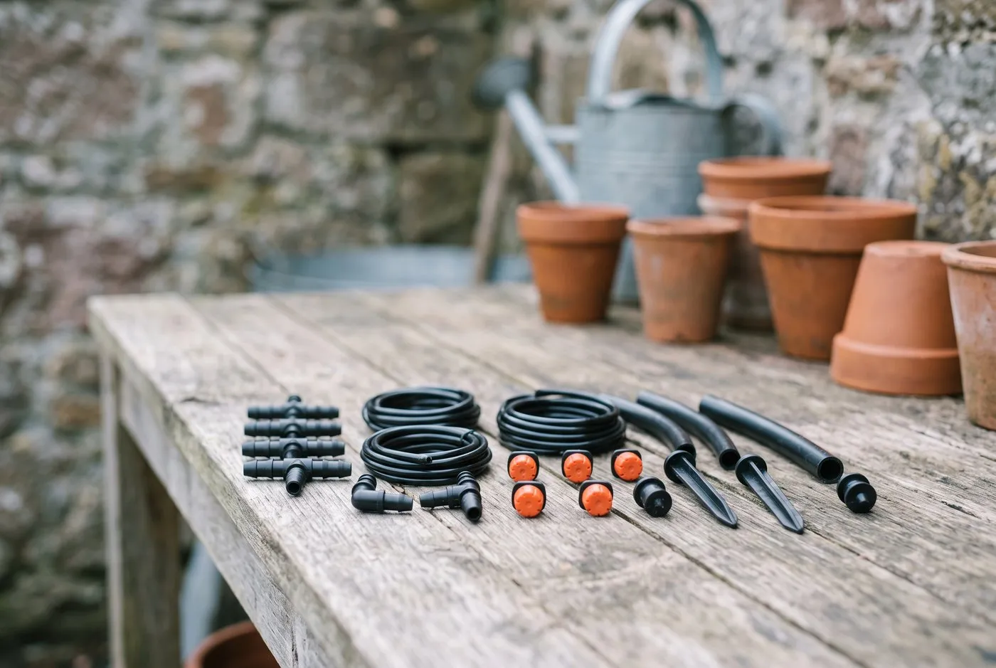 Micro-drip irrigation connectors and adjustable drippers laid out on a potting bench in a Scottish walled garden